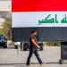 عراقي يمر أمام لوحة إعلانية تحمل العلم العراقي في ساحة التحرير بوسط بغداد 22 سبتمبر 2026 (أ.ف.ب)