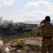جندي في الجيش اللبناني يستخدم هاتفه لتصوير دخان يتصاعد من مبنى في زوطر الشرقية تعرض لضربة إسرائيلية (رويترز)