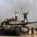 فلسطينيون يحتفلون على ظهر دبابة إسرائيلية على الجدار العازل قرب خان يونس في جنوب قطاع غزة يوم 7 أكتوبر 2023 (أ.ب)