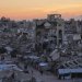 فلسطينيون يسيرون وسط مبانٍ مدمرة في غزة (رويترز)
