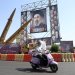 إيرانية تقود دراجتها أمام صواريخ «ذوالفقار» ولوحة تحمل صورة المرشد الإيراني مجتبى خامنئي في ساحة بهارستان وسط طهران يوم الأحد (إ.ب.أ)